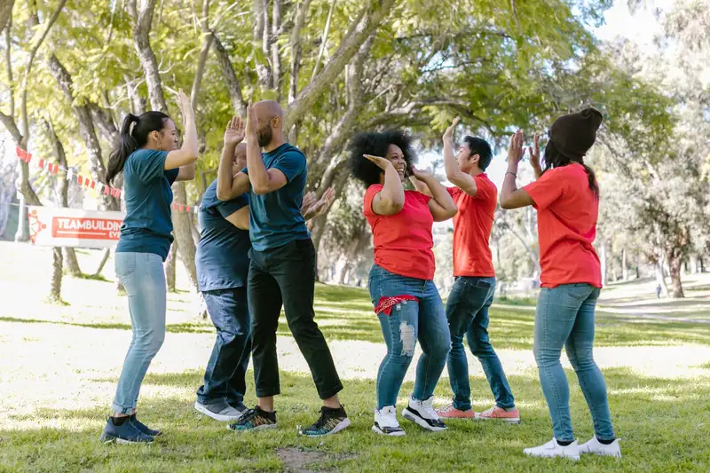 Diverse group of adults enjoying an energetic team building activity in a sunny park.
